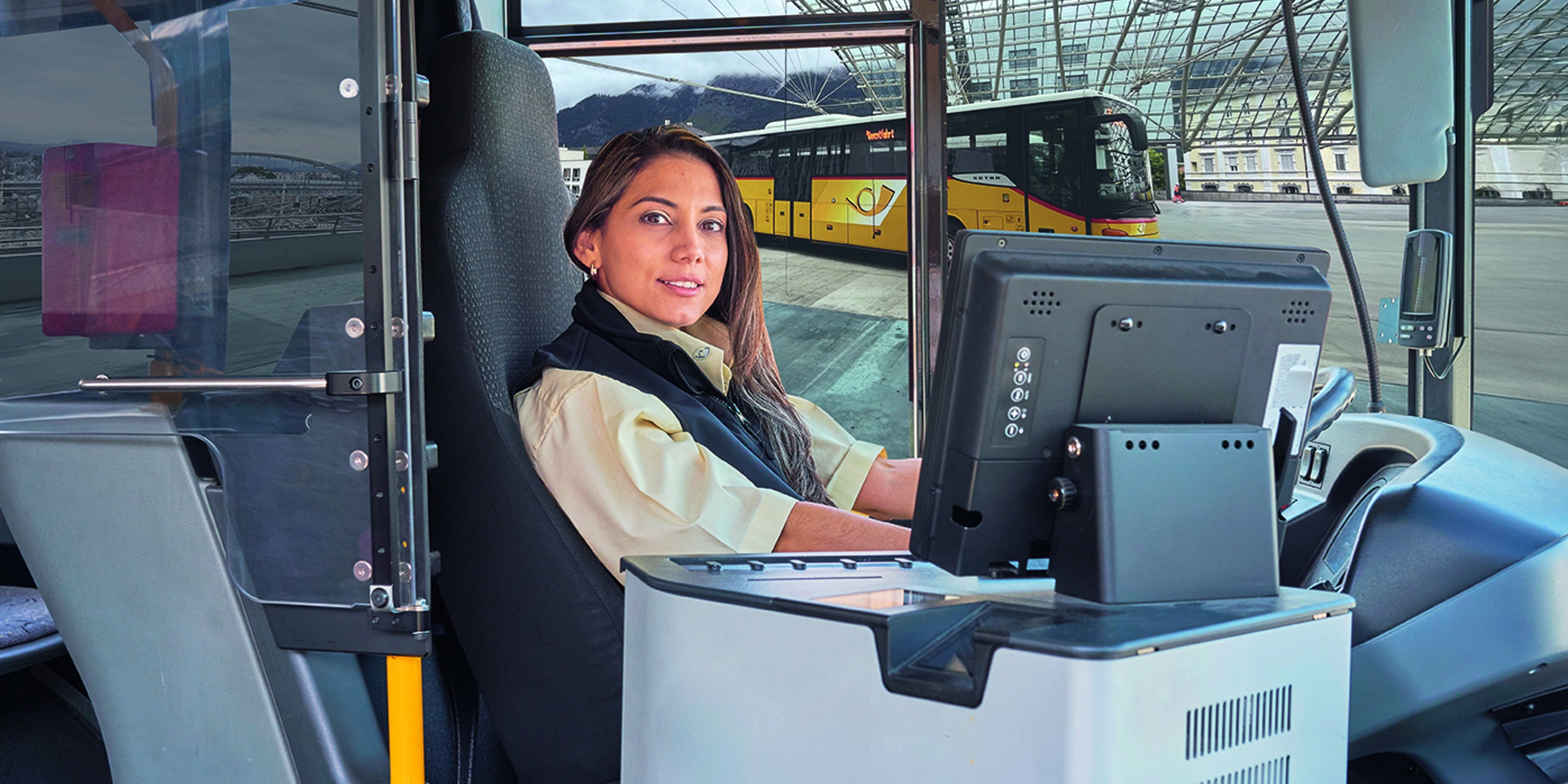 Eine PostAuto-Mitarbeiterin am Steuer des Postautos